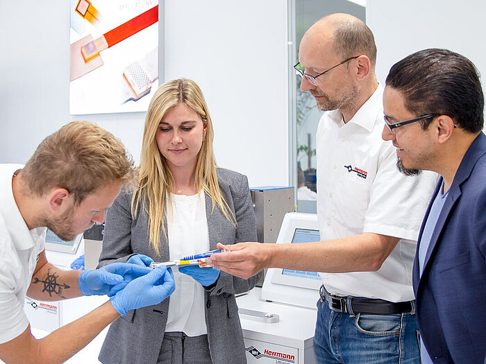 Mehrere Herrmann Ultraschall Mitarbeiter betrachten das Ergebnis einer Metallschweißung